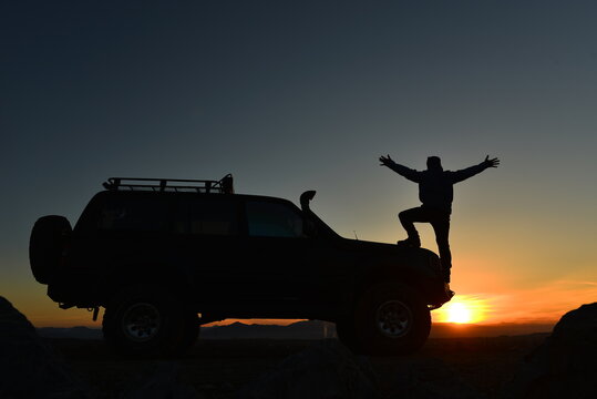 Silhouette of a Traveler and Off Road SUV at Sunset