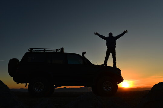 Freedom on the Road: Adventurer with 4x4 Vehicle at Sunset