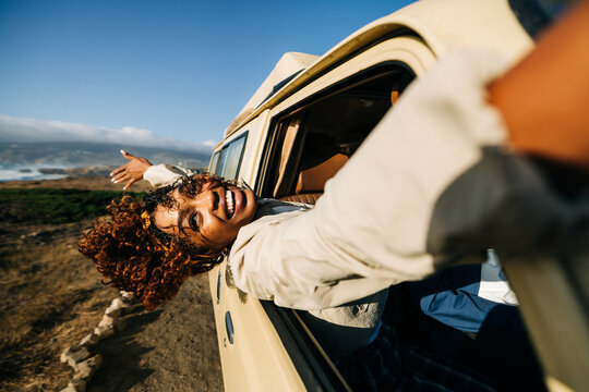 Happy woman leans from car window during road trip adventure
