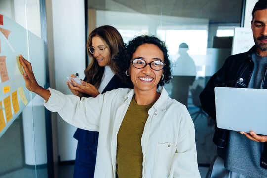 Smiling team leads planning session with sticky notes.