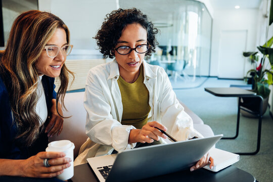 Two women review business ideas on laptop