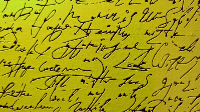 Abstract closeup of vintage cursive handwriting in black ink on a bright yellow textured background for creative design projects