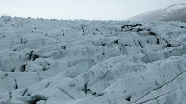 Solheimajokull glacier displays densely fractured blue ice, deep crevasses and rugged compressed formations in the Katla region of South Iceland, drone forward flyover