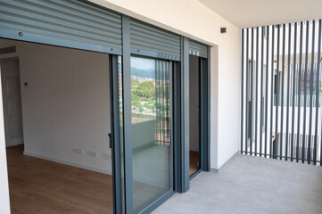 Obraz premium Modern apartment balcony with sliding glass doors and shutters