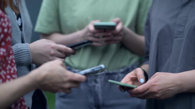 Group international young friends gathered using mobile phones. people looking cells watching videos on networks. Addiction to technology of gen Z. smartphone Social media. Chatting texting messages
