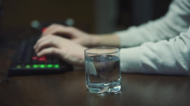 Initial signs and precursors of an earthquake. Hands typing on keyboard, glass of water on table, power outage at moment first tremors hit. Signs of earthquake indicating need to evacuate building.
