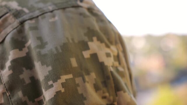 Close up of military blue-yellow chevron on shoulder of ukrainian soldier while going at countryside. This a powerful symbol of national identity, courage and unity. Concept of invasion resistance