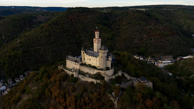 Aerial view of Marksburg castle perched on a hilltop surrounded by dense forest and rolling hills in Braubach, Rhineland-Palatinate, Germany.