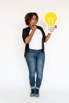 Person holding a large light bulb cutout, thoughtful expression.