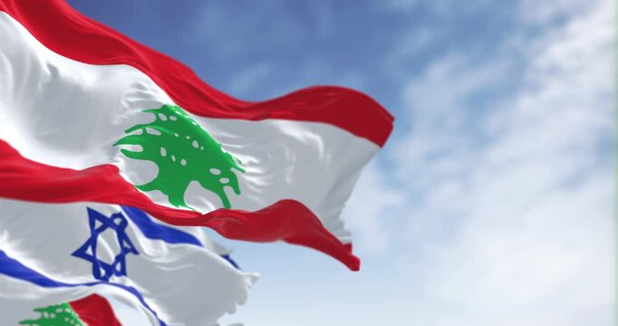 Flags of Israel and Lebanon waving in the wind on a clear day