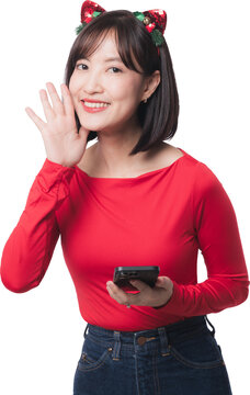 Happy young asian woman holding smartphone cheering holiday offer discount promoting seasonal christmas sale black friday shopping deal event standing against isolated plain background