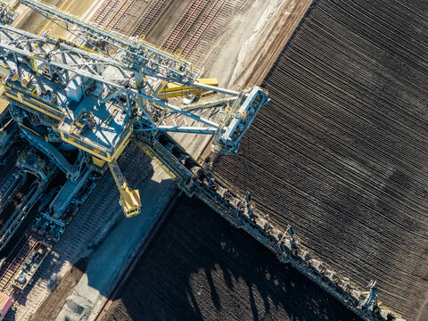 Aerial view of Tagebau Welzow-Sud brown coal open-pit mine with a large bucket-wheel excavator operating on dark soil in Spremberg, Brandenburg, Germany.