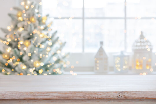 Light wooden table top with blurred Christmas tree and festive background for holiday product display
