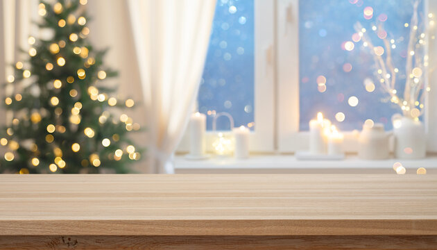 Cozy wooden table top with blurred Christmas tree and winter window holiday background with candles