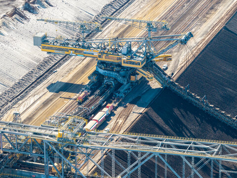 Aerial view of the Tagebau Welzow-Sud brown coal open-pit mine, featuring a massive bucket-wheel excavator operating along the dark earth terraces in Spremberg, Brandenburg, Germany.