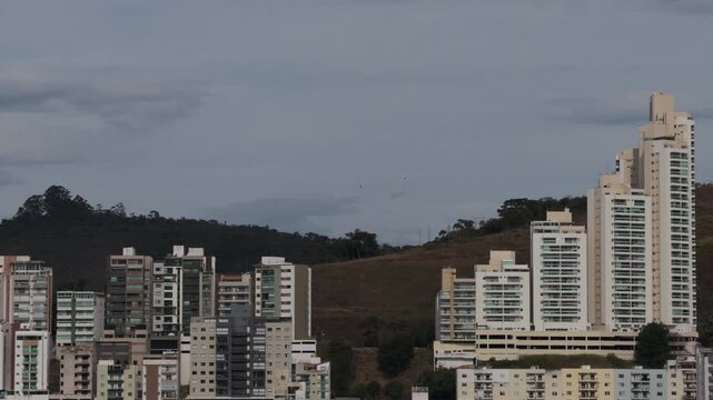 Modern White Residential Towers Beneath Cloudy Hillside Skyline