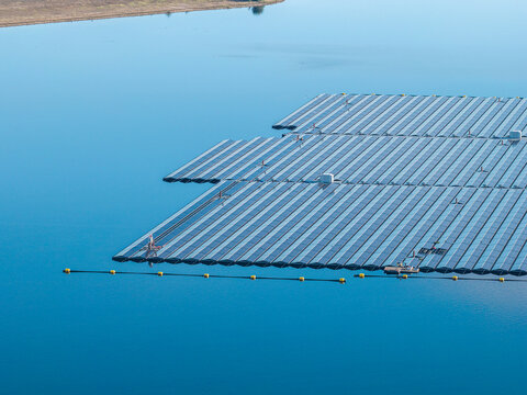 Aerial view of the floating solar farm on Cottbuser Ostsee, featuring rows of solar panels on the calm blue water surface at the former open pit mine in Cottbus, Brandenburg, Germany.
