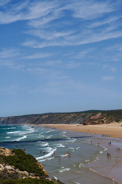 Scenic view of Praia da Bordeira in Algarve, Portugal, with tourists enjoying the sandy beach and atlantic waves