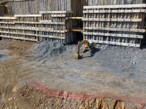 Aerial view of an excavator working at a construction site with concrete retaining walls and excavated earth in Istanbul, Istanbul, Turkiye.