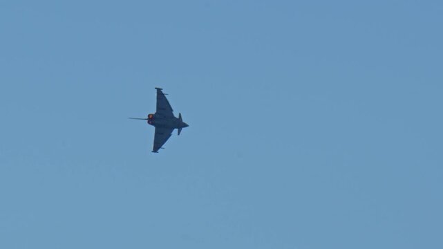 Powerful European fighter jet flying in the sky, executing a sharp turn with visible afterburner glow, showcasing advanced military aviation technology and pilot skill