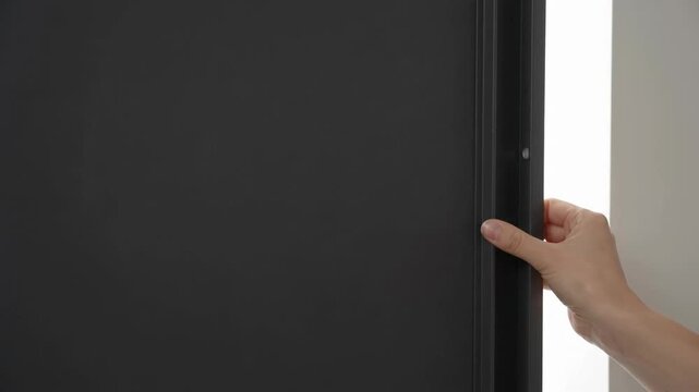 Hand Pressing Blackout Blind Into Window Frame To Block Light
