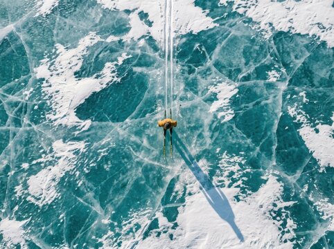 Frozen lake aerial view with lone hiker and dramatic ice texture
