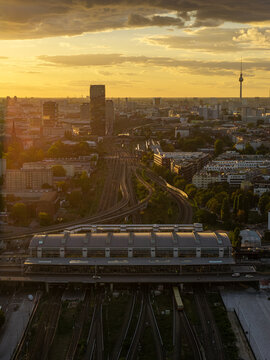 Aerial view of Ostkreuz station with its distinctive roof structure, complex railway tracks, and the Berlin urban skyline during golden hour in Berlin, Berlin, Germany.