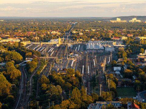 Aerial view of ICE Werk Berlin Rummelsburg train maintenance facility with numerous tracks and trains surrounded by lush greenery in the golden hour light in Berlin, Berlin, Germany.