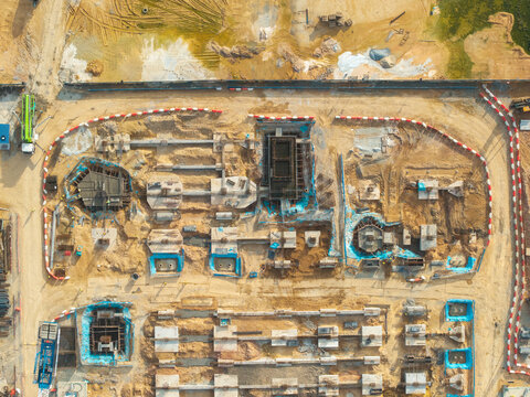 Aerial view of a construction site featuring concrete foundations, excavated earth, and blue protective sheeting in Bukit Tambun, Penang, Malaysia.