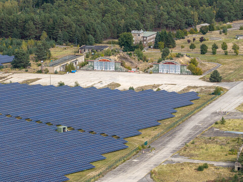 Aerial view of the solar field at the former military airfield in Preschen, featuring historic hangars, concrete runways, and taxiways in Neisse-Malxetal, Brandenburg, Germany.