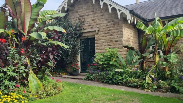 Traditional British Stone Cottage with Flower Garden and Banana Leaves