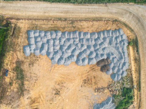 Aerial view of construction area with large piles of gravel and sand on a cleared dirt site in Bukit Tambun, Penang, Malaysia.