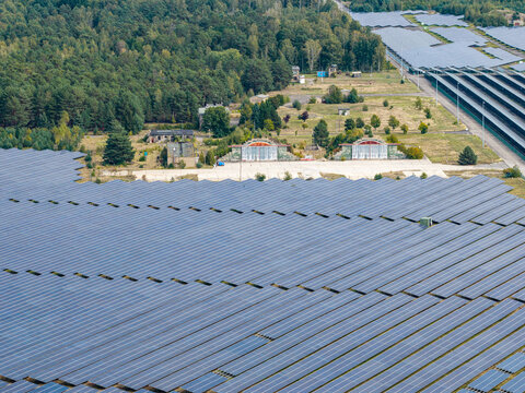 Aerial view of the former military airfield in Preschen now converted into a large solar farm with historic hangars and rows of photovoltaic panels, Neisse-Malxetal, Brandenburg, Germany.