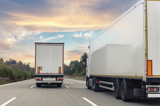 Tail view white blank modern delivery big shipment cargo commercial semi trailer truck moving motorway road city urban suburb. Business distribution logistics service. Lorry driving highway sunset
