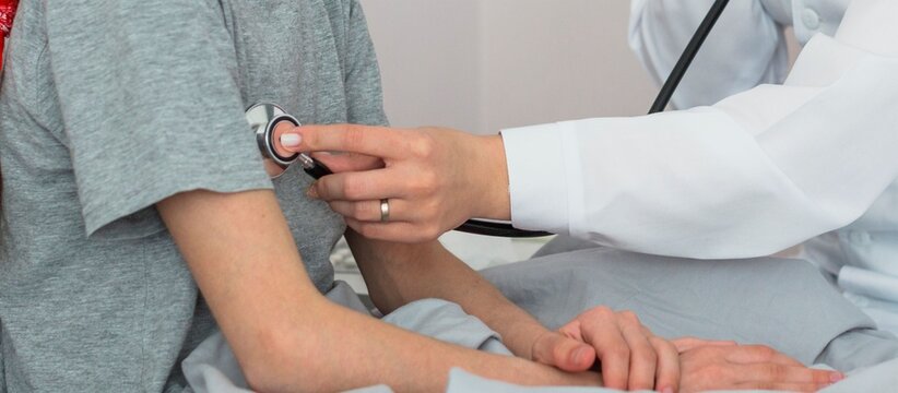 Doctor listening to patient's heartbeat with stethoscope during checkup