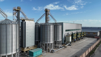 Large industrial metal silo storage facility complex under blue sky © zhu difeng
