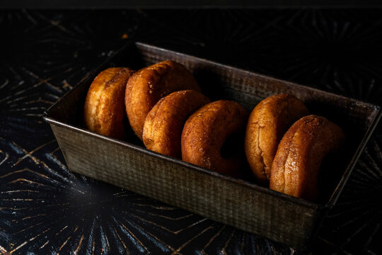Donuts in a metal baking loaf pan on a dark surface 