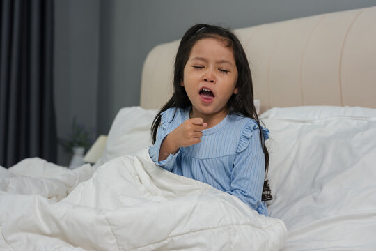 sick preschoool child girl coughing in bed with cold symptoms