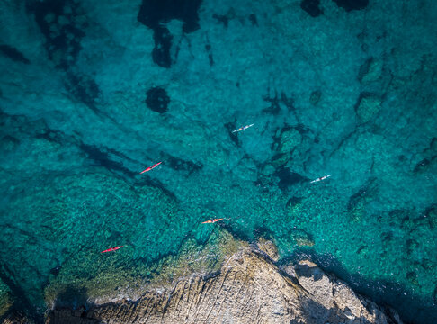 Aerial view of kayakers paddling in clear turquoise water off Lakka, Paxos, Ionian Islands, Greece