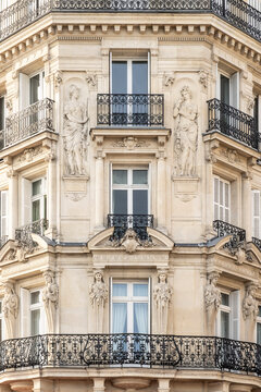Detail of ornate Haussmann-era building facade with sculptural caryatids and wrought iron balconies, Paris, France