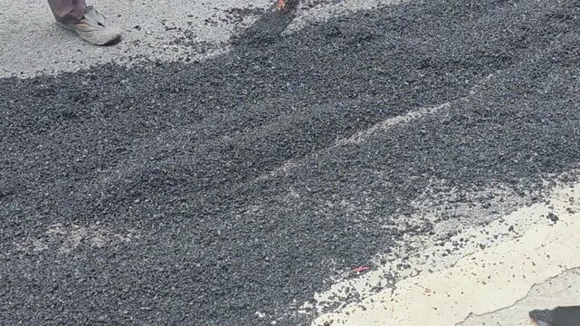 Video of road repair by laying asphalt. Road worker repairs damaged asphalt with paving equipment during street maintenance and infrastructure service operation.	