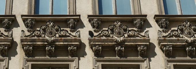 Detail of a weathered historic facade in Goerlitz with repeating mascarons, ornamental window crowns and sculptural architectural decoration showing visible signs of aging. © Frank