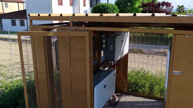 Aerial view of a metal technical enclosure containing electrical equipment and solar inverters situated in a rural area in Faenza, Emilia-Romagna, Italy.