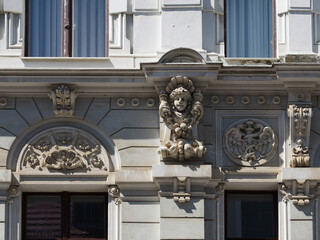 Detail of an ornate historic facade in Goerlitz featuring a sculpted female head as a mascaron, floral ornaments, rosettes and a decorative relief medallion between tall windows. © Frank