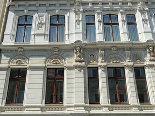Richly decorated historic townhouse facade in Goerlitz with tall windows, mascarons, floral ornaments, rosettes and decorative reliefs in the Historicist style. © Frank