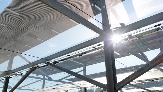 Aerial view of modern solar panels mounted on a metal structure, capturing sunlight and reflecting the clear blue sky in Faenza, Emilia-Romagna, Italy.