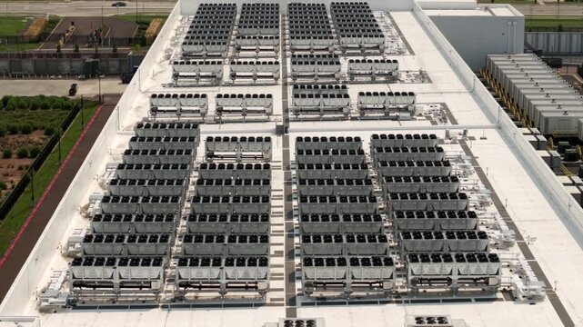 Roof of a data center, featuring industrial buildings and rooftop cooling systems. Slow drone backwards flight.