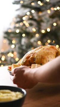 Roasted turkey being served at a festive Christmas dinner table surrounded by traditional holiday side dishes and seasonal decorations.