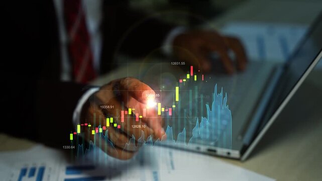 Businessman using a laptop with glowing hologram stock market charts and financial data overlay animation, showing investment analysis and digital trading in a dark office.