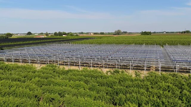 Aerial view of a large agricultural field with metal support structures for cultivation under a clear blue sky in Faenza, Emilia-Romagna, Italy.